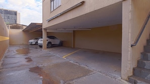 Garagem de estacionamento com dois carros, piso de concreto e escada que leva a um nível superior.