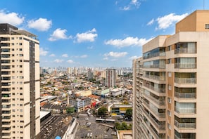 Un edifici alt amb diversos balcons, un paisatge urbà de fons i un cel serè.