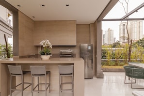 Una cocina moderna con una isla central, electrodomésticos de acero inoxidable y vistas a un paisaje urbano.