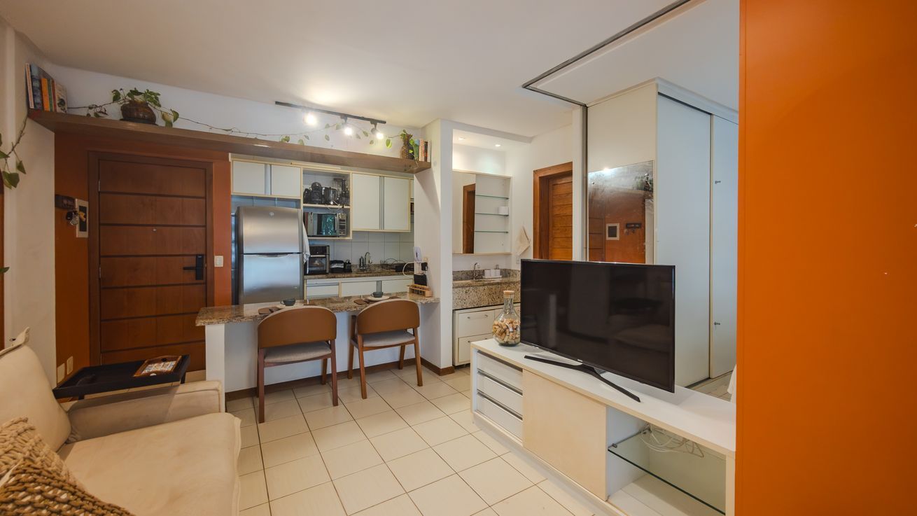 Un espace de vie compact comprenant un coin cuisine, un coin repas et un coin salon avec un téléviseur.