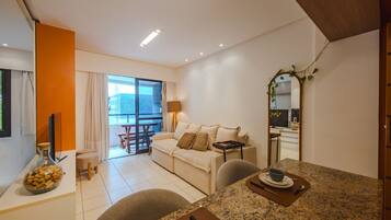 A modern living room with a sofa, dining table, and a balcony with a view.