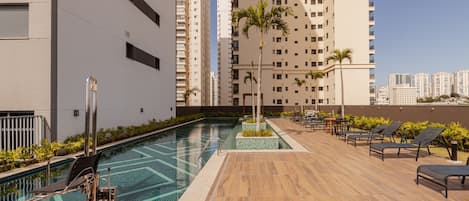 A rooftop pool area with lounge chairs and a diving board.