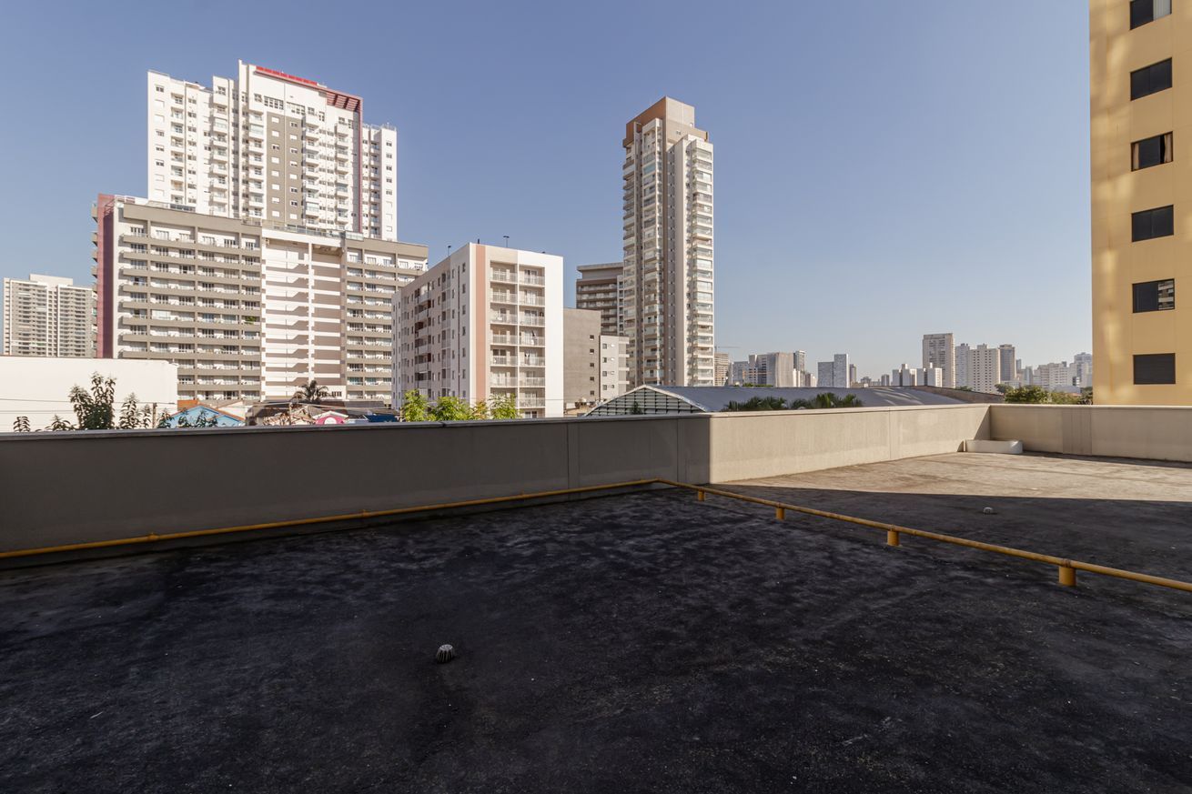 A rooftop with a view of high-rise buildings, a clear sky, and a concrete floor.