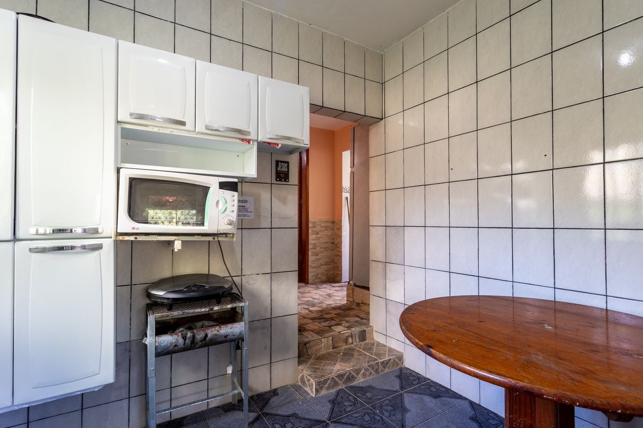 A compact kitchen with a microwave, a small refrigerator, and a wooden table.