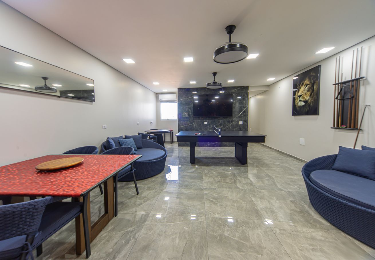 A modern living room with a dining table, sofas, a TV, and a pool table.
