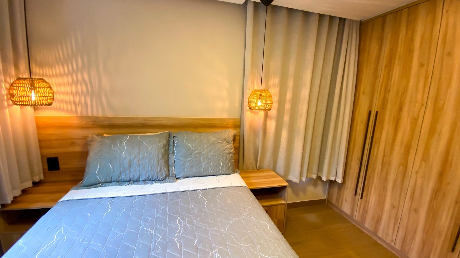 Une chambre à coucher avec un lit, une tête de lit en bois, deux lampes de chevet et une armoire en bois.