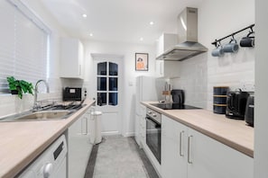 Cocina compacta con lavamanos, estufa, horno y cafetera.