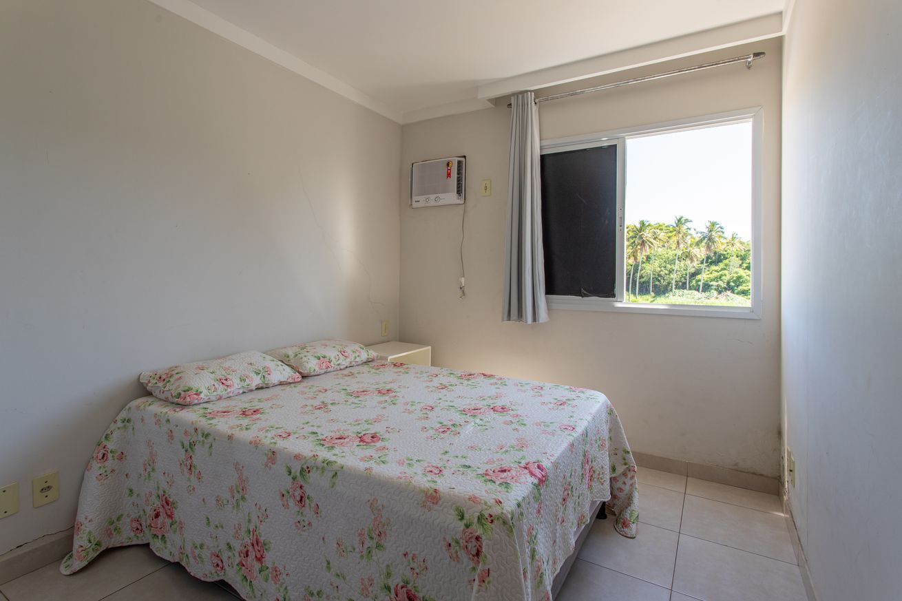 A bedroom with a bed, a window, and a wall-mounted air conditioner.
