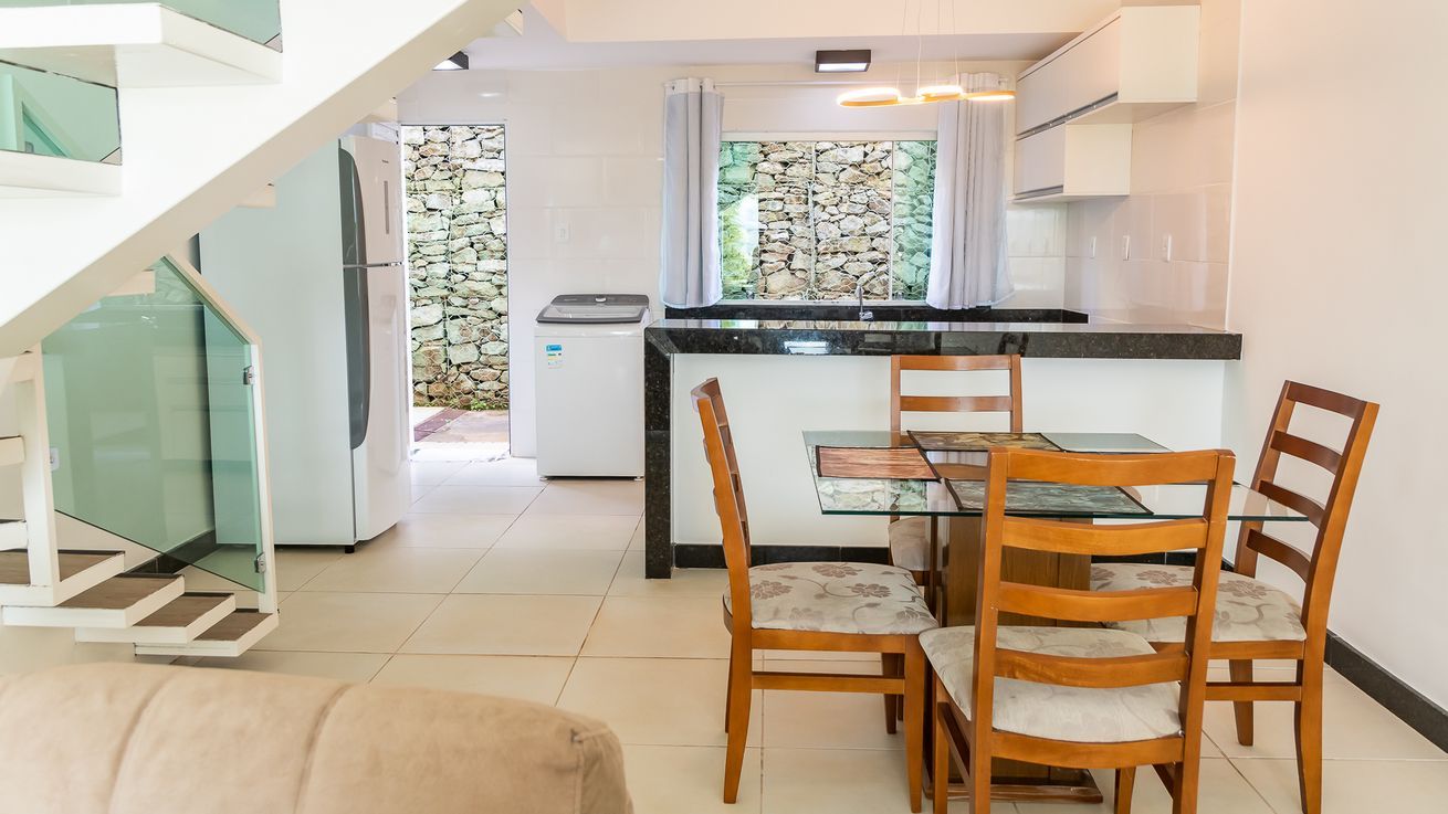 Une cuisine moderne avec un coin repas, un escalier et une vue sur un mur en pierre.