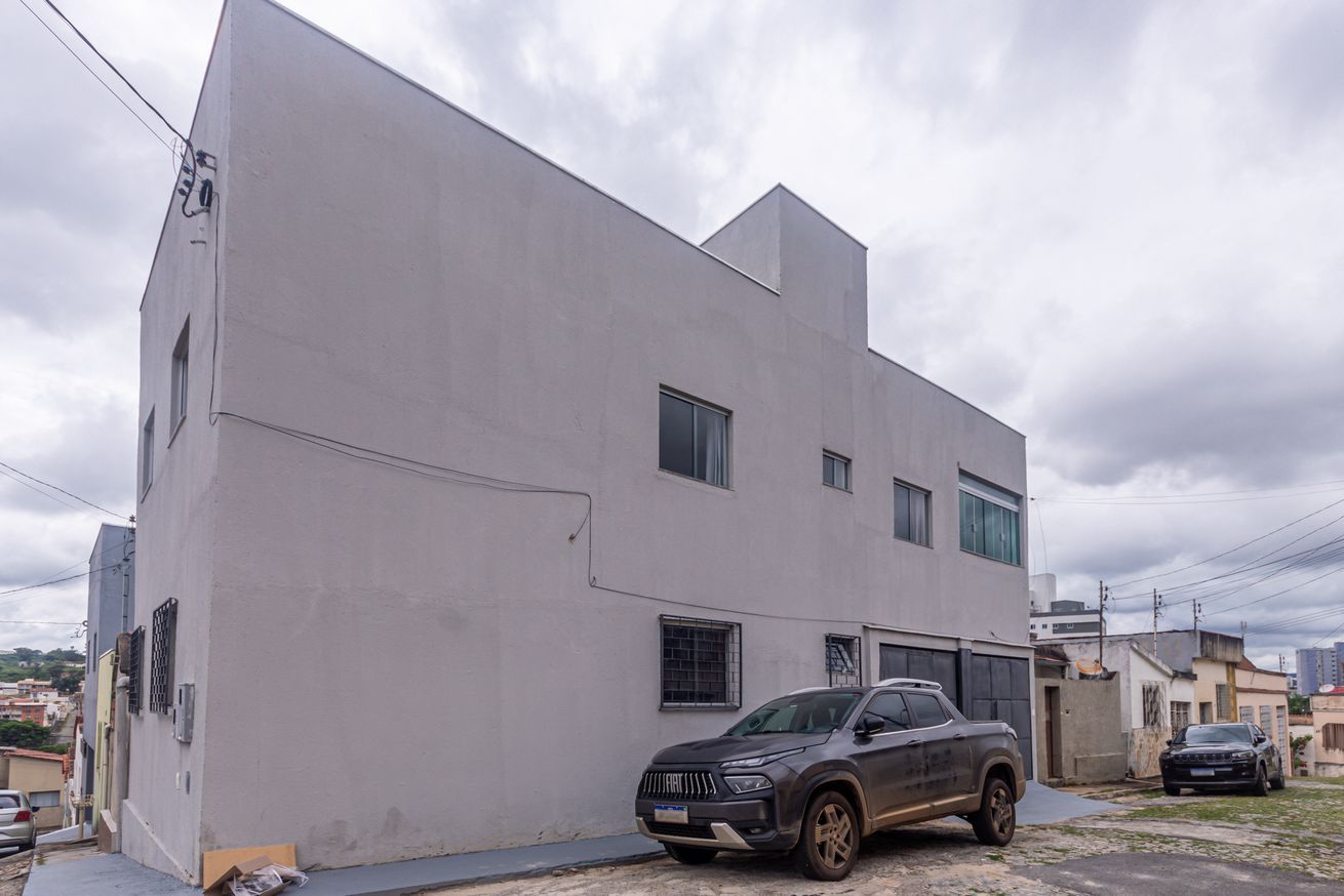 Un edifici modern de dues plantes amb teulada plana i una SUV estacionada.
