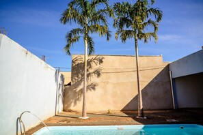 A swimming pool with a palm tree in the background. - Casa c Piscina, Churrasqueira perto do Rio Grande (Itapagipe)