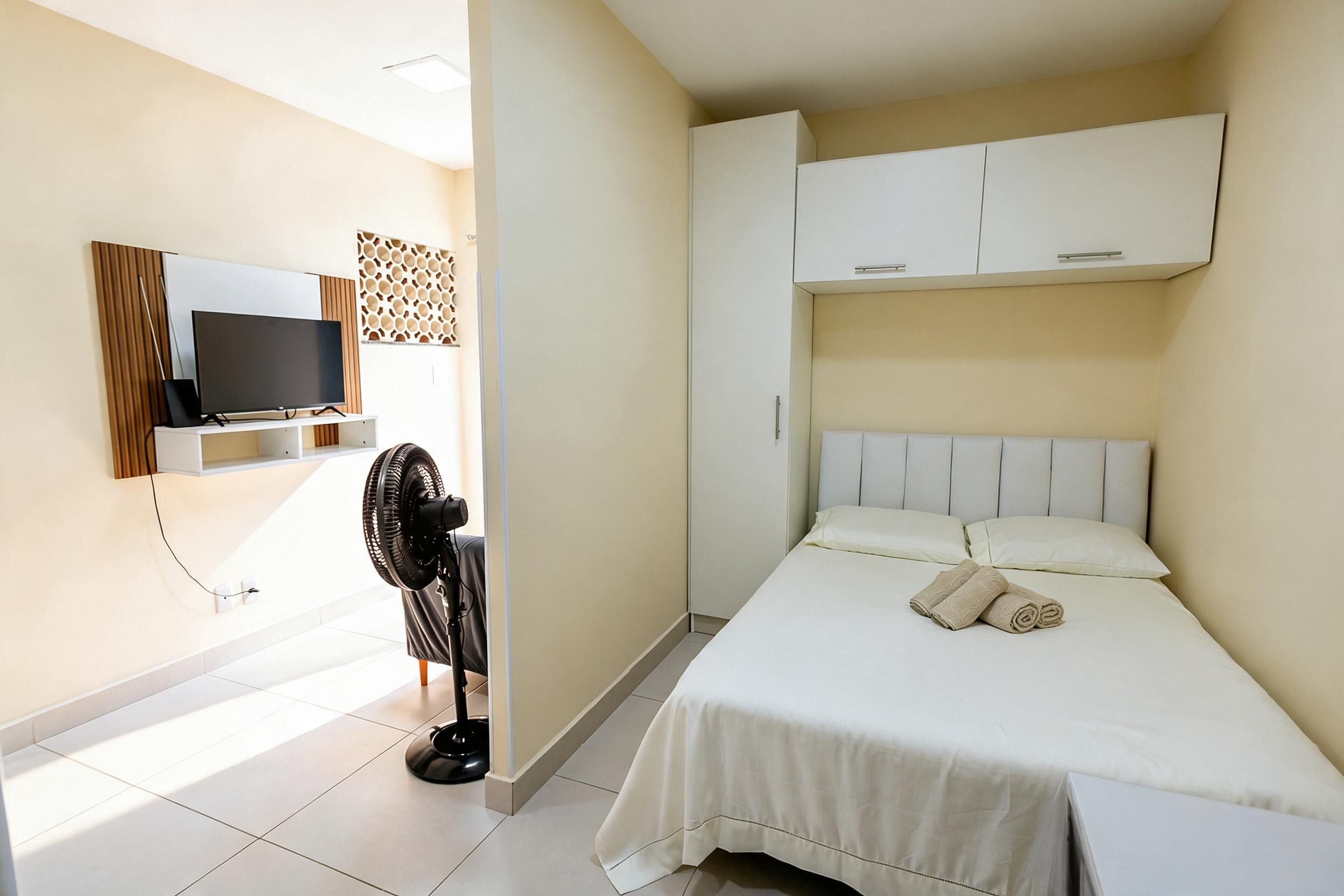 A hotel room with a bed, a TV, a desk, and a wardrobe.