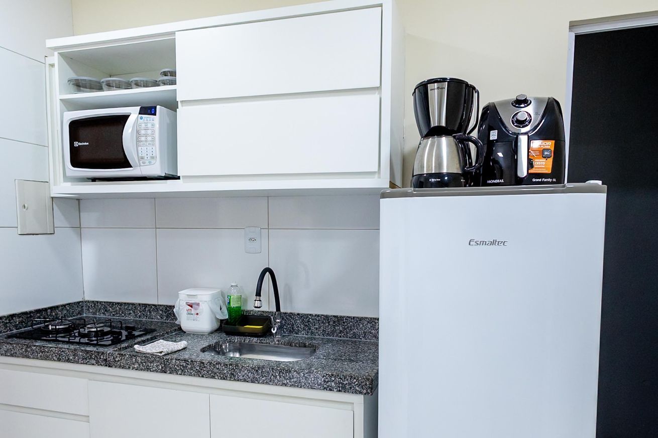 A kitchen with a microwave, coffee maker, and refrigerator.