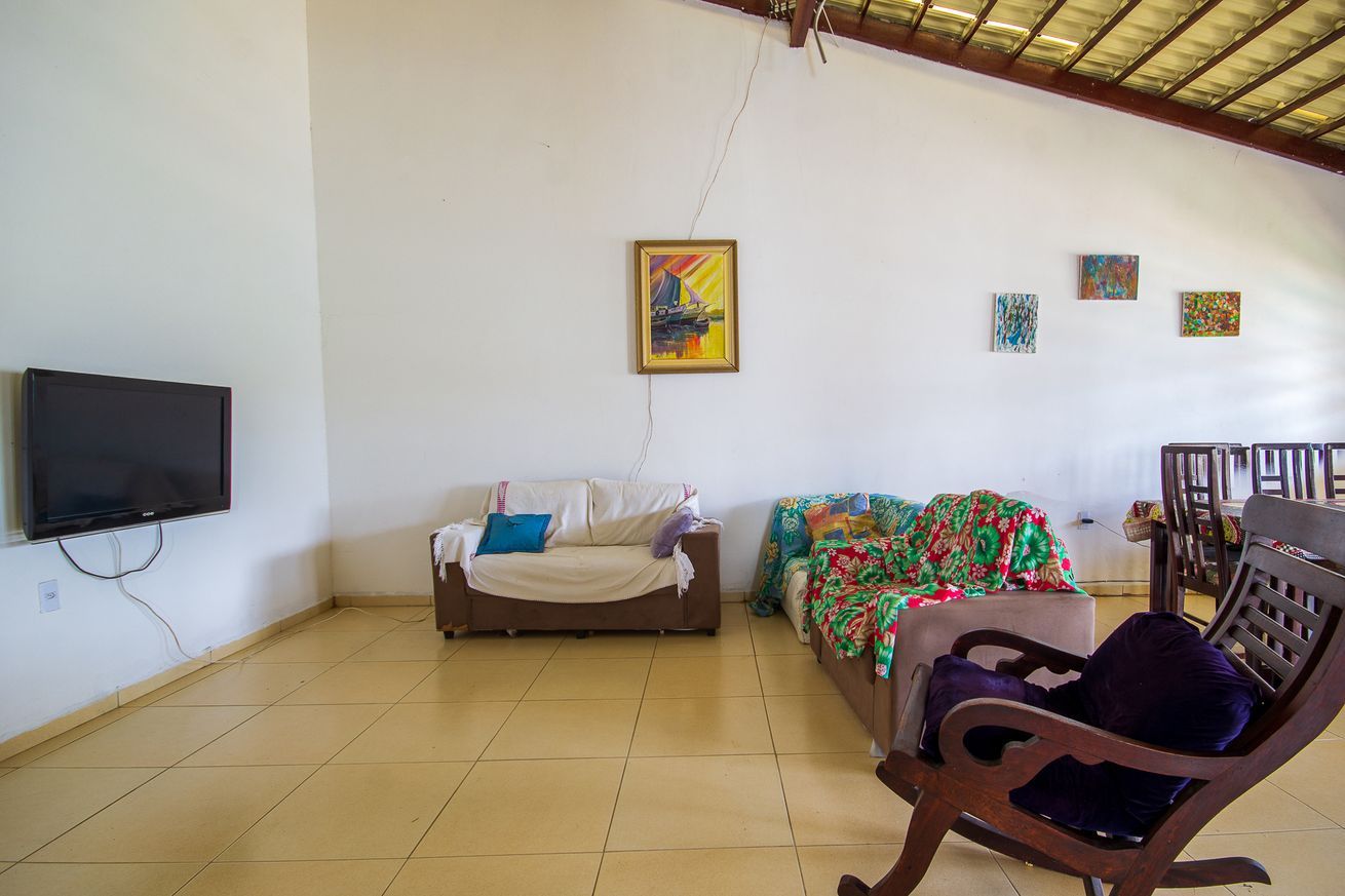 Ein Zimmer mit Fernseher, Sofa, Sessel und Bildern an der Wand.