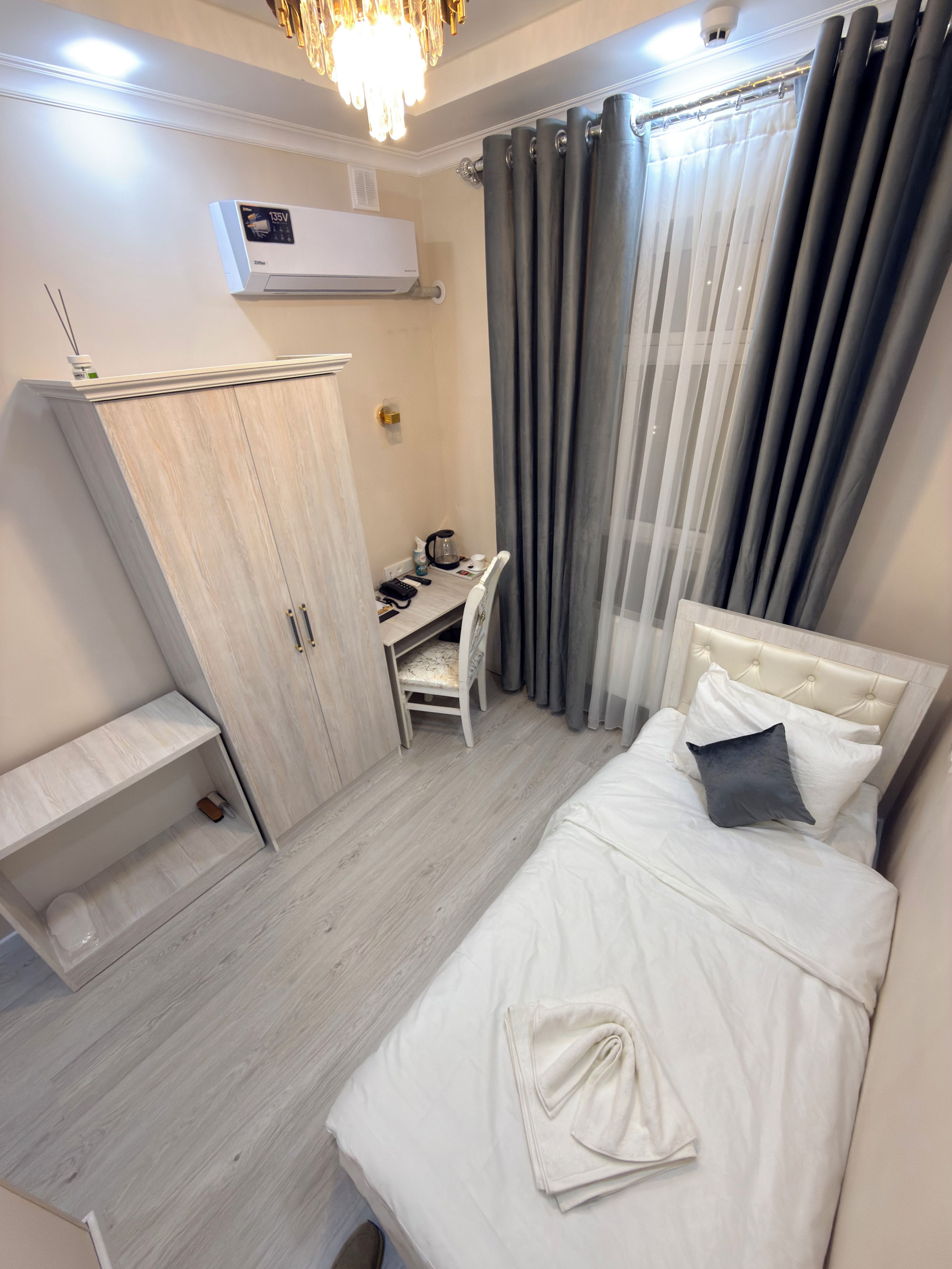 Une chambre à coucher comprenant un lit, un bureau, une chaise, une armoire et un appareil de climatisation.