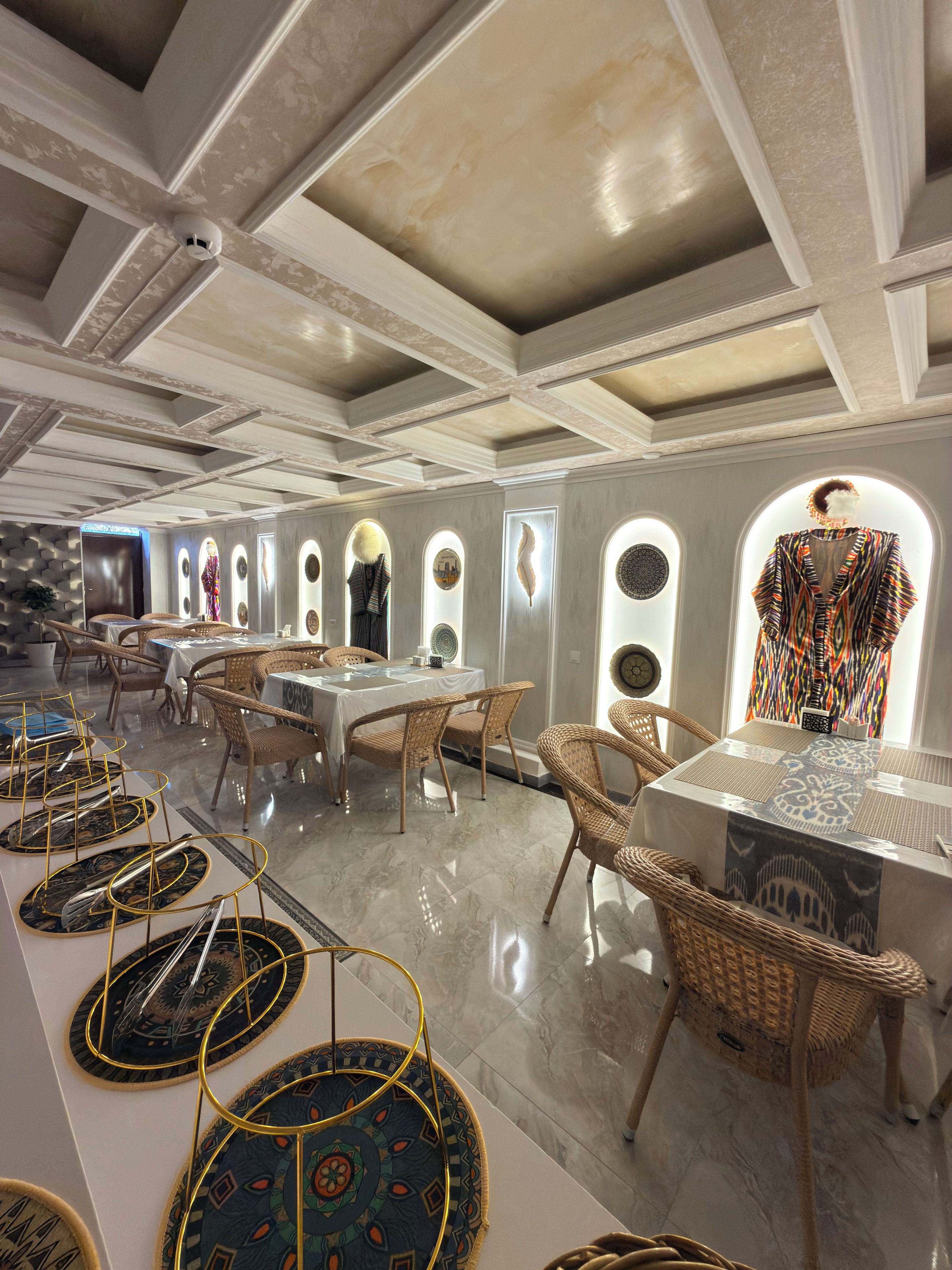 Un espace repas doté d’un plafond haut, de murs à motifs et offrant une vue à travers des fenêtres en arc de cercle.