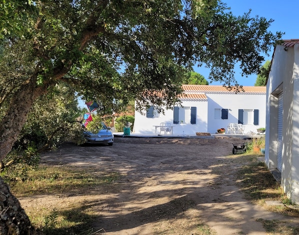 A white building with a tiled roof, a dirt path, and a parked car. - New Listing (L'Épine)