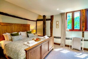 Una camera da letto tradizionale con un letto grande, una testata in legno e una finestra con tende.