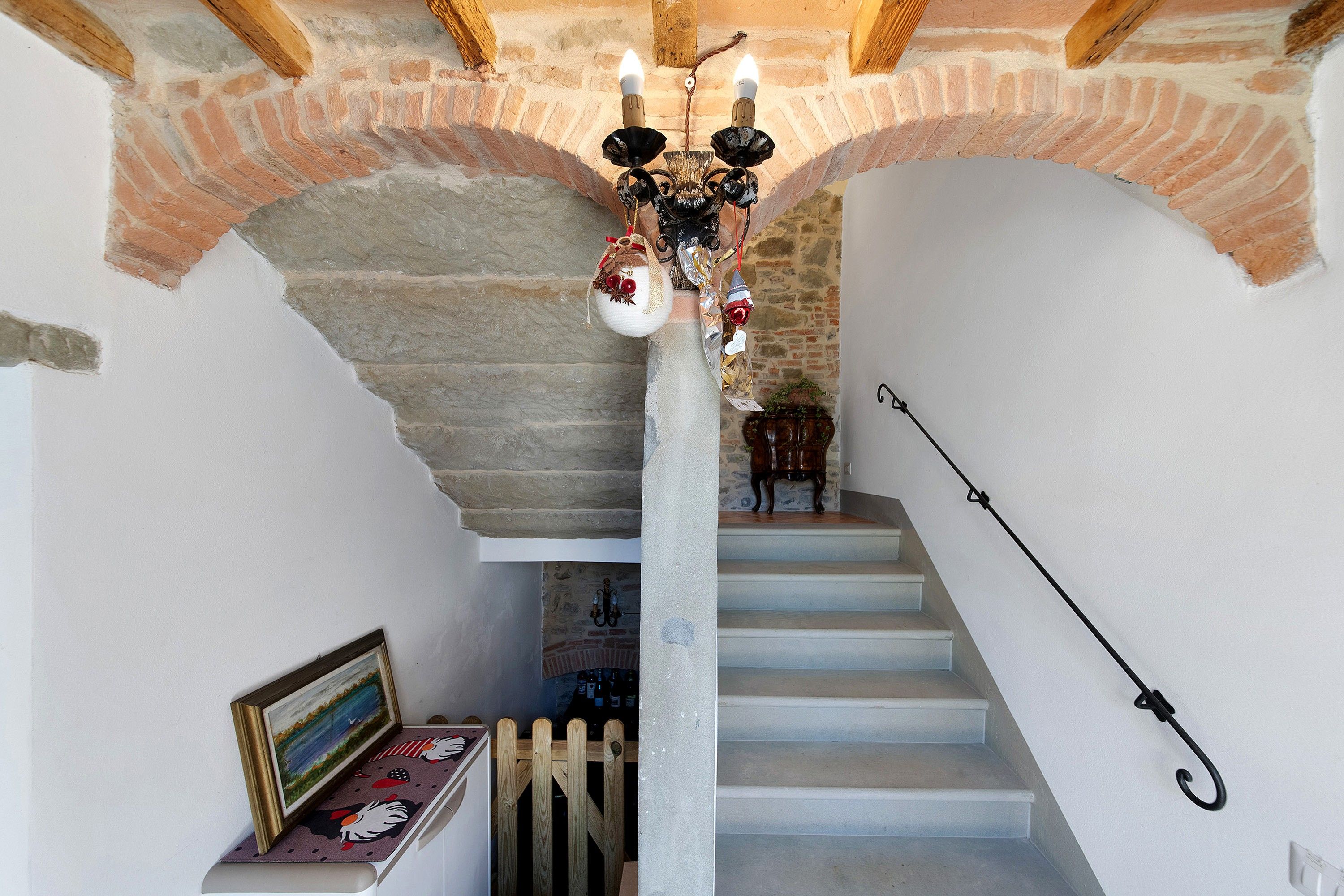 A staircase with a chandelier, a framed picture, and a wooden fence.