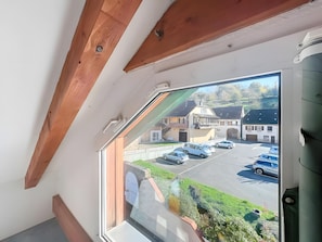 A room with a large window overlooking a parking area and buildings.