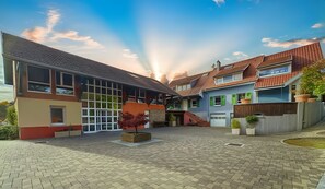 Um pátio com um caminho pavimentado, um edifício com grandes janelas e um céu limpo.