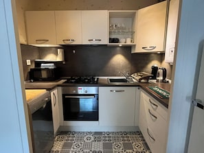 Cocina pequeña equipada con microondas, estufa, horno y lavamanos.