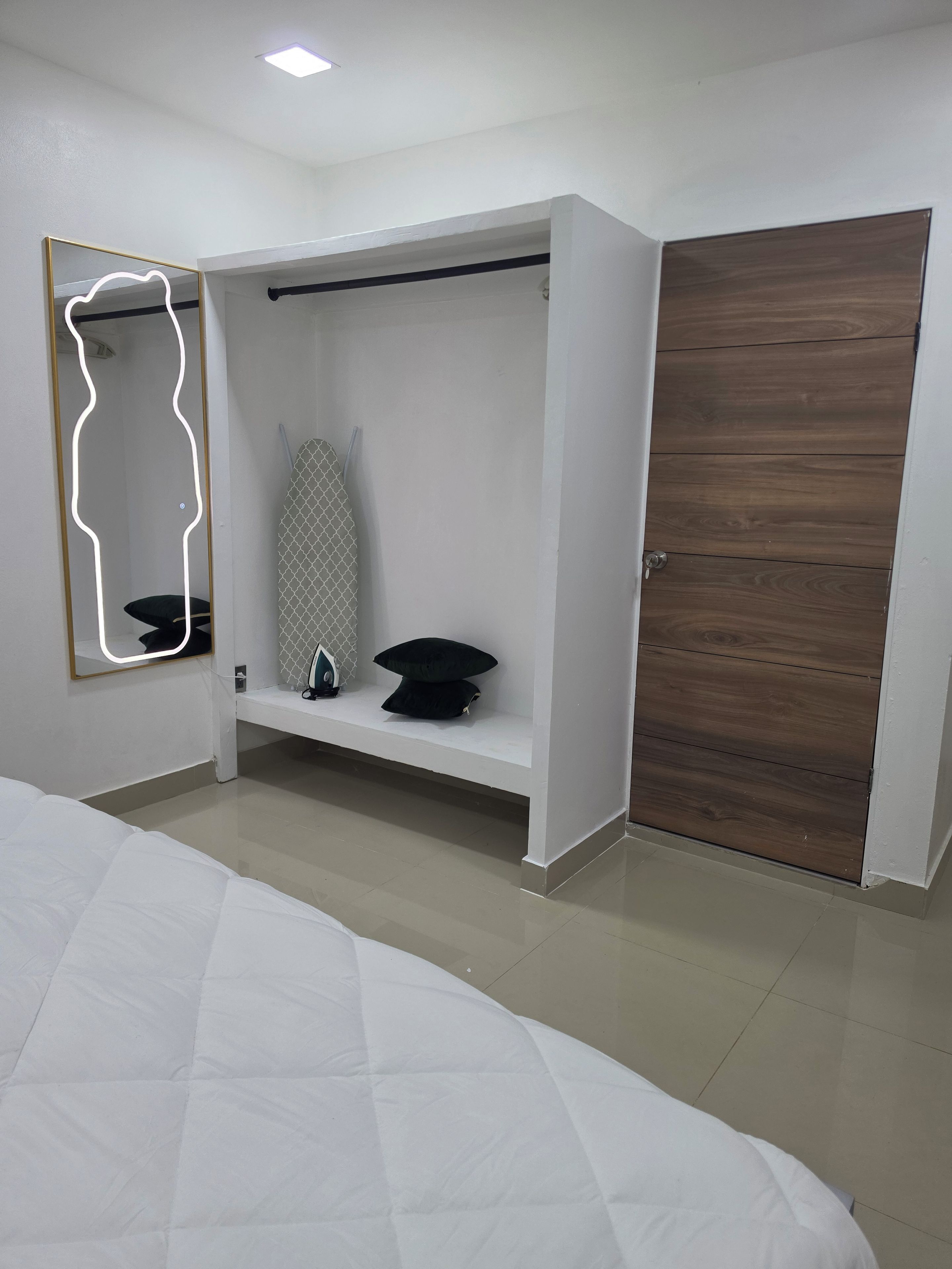 Un dormitorio con una cama, un armario, un espejo y una estantería con un objeto estampado.