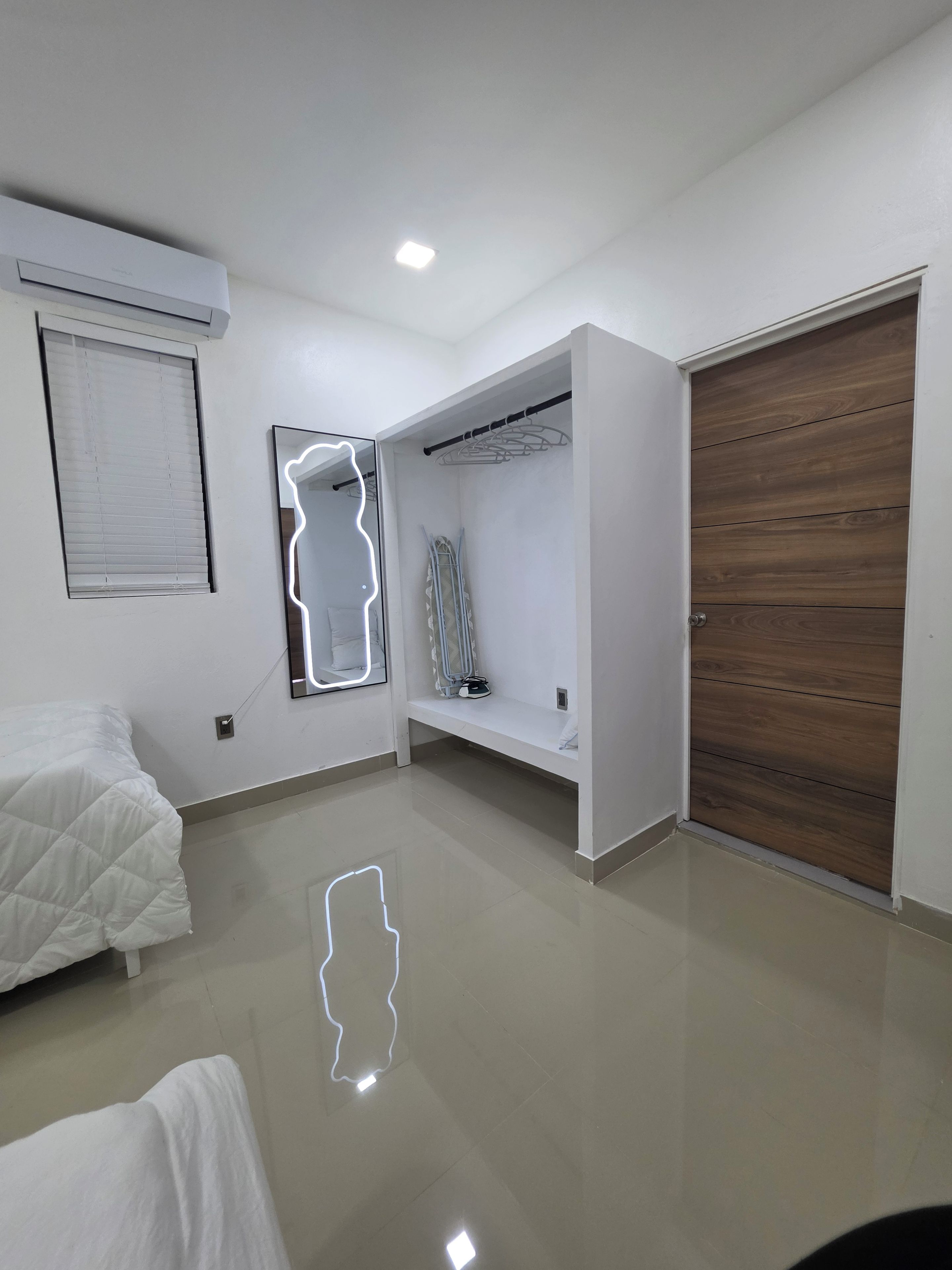 Ein modernes Schlafzimmer mit Bett, Kleiderschrank, Spiegel und Deckenleuchte.