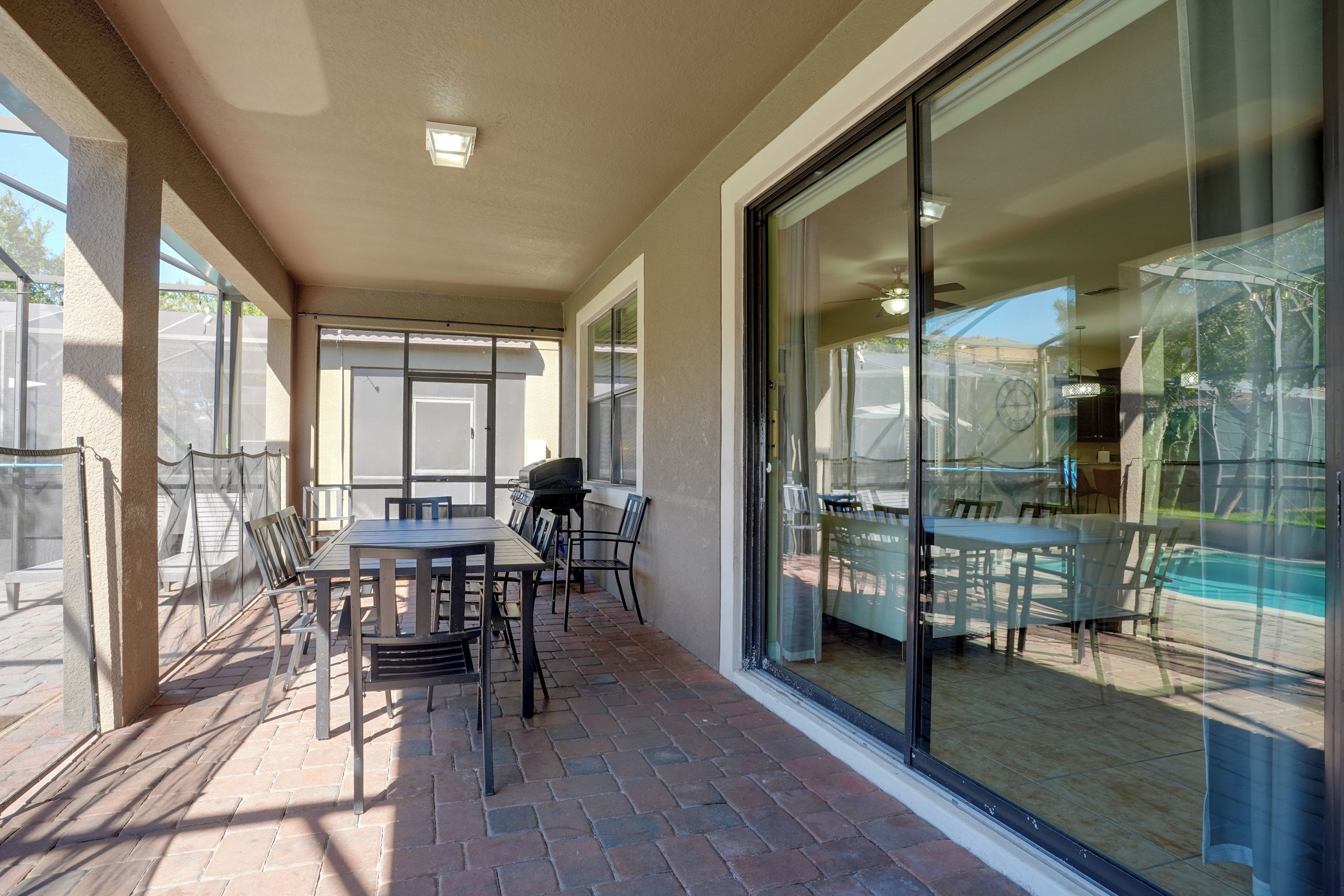 A covered patio area with outdoor furniture and a barbecue grill.