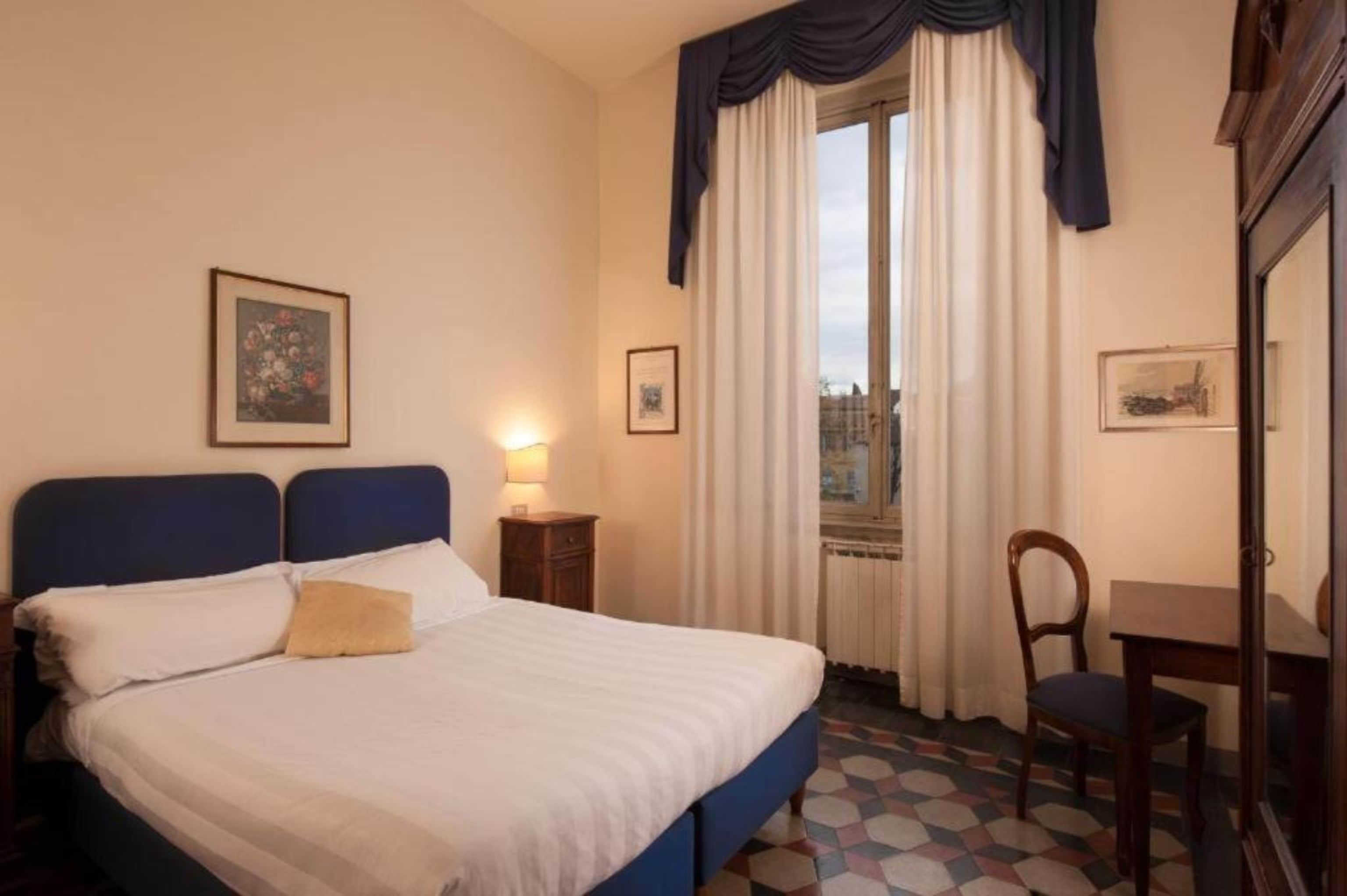 Una habitación de hotel con una cama, un escritorio y una silla.