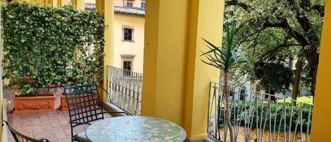 A terrace with a table and chairs, surrounded by yellow walls and potted plants.
