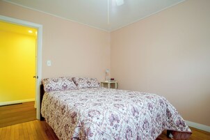 Un dormitorio con una cama, una mesita de noche con lámpara y un reloj de pared.