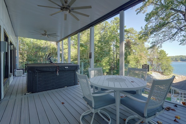 A covered outdoor deck with a round table and chairs, a grill, and a view of a lake. - Private Dock! Luxury Beachfront Lake Lanier Escape (Buford)