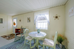 A room with a round table, two chairs, a window with lace curtains, a door, and a wall clock. - Harrisburg Unit w/ Mtn Views & Backyard (Harrisburg)