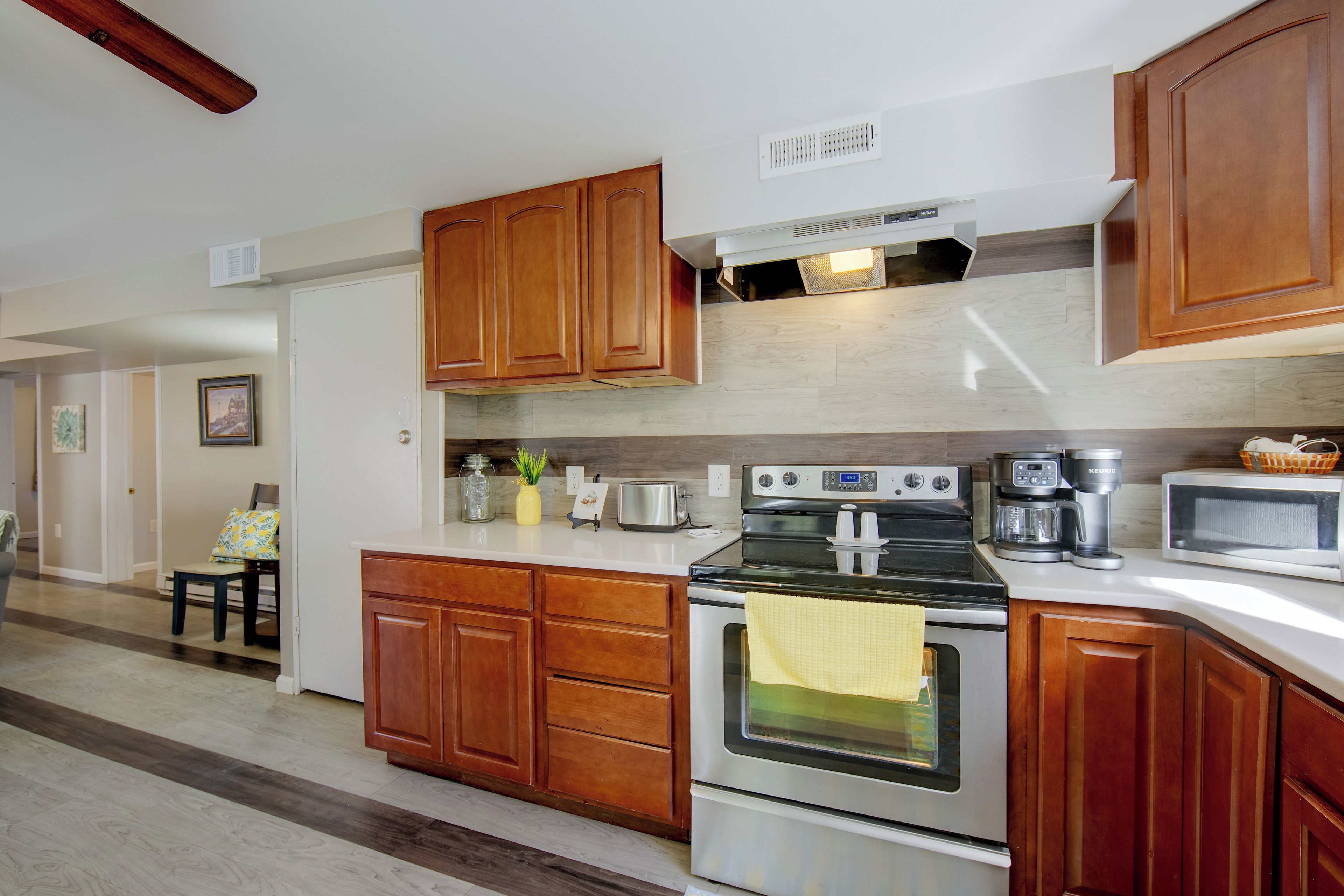 A kitchen with wooden cabinets, a stove, a microwave, and a coffee maker.