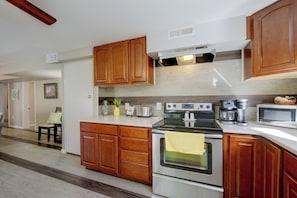 A kitchen with wooden cabinets, a stove, a microwave, and a coffee maker. - Harrisburg Unit w/ Mtn Views & Backyard (Harrisburg)