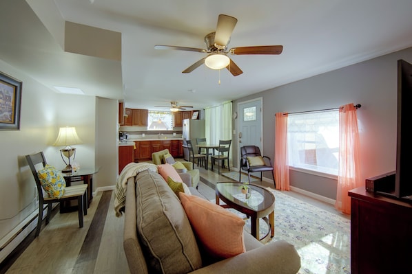 A living room with a sofa, a dining table, a kitchen in the background, and a ceiling fan. - Harrisburg Unit w/ Mtn Views & Backyard (Harrisburg)
