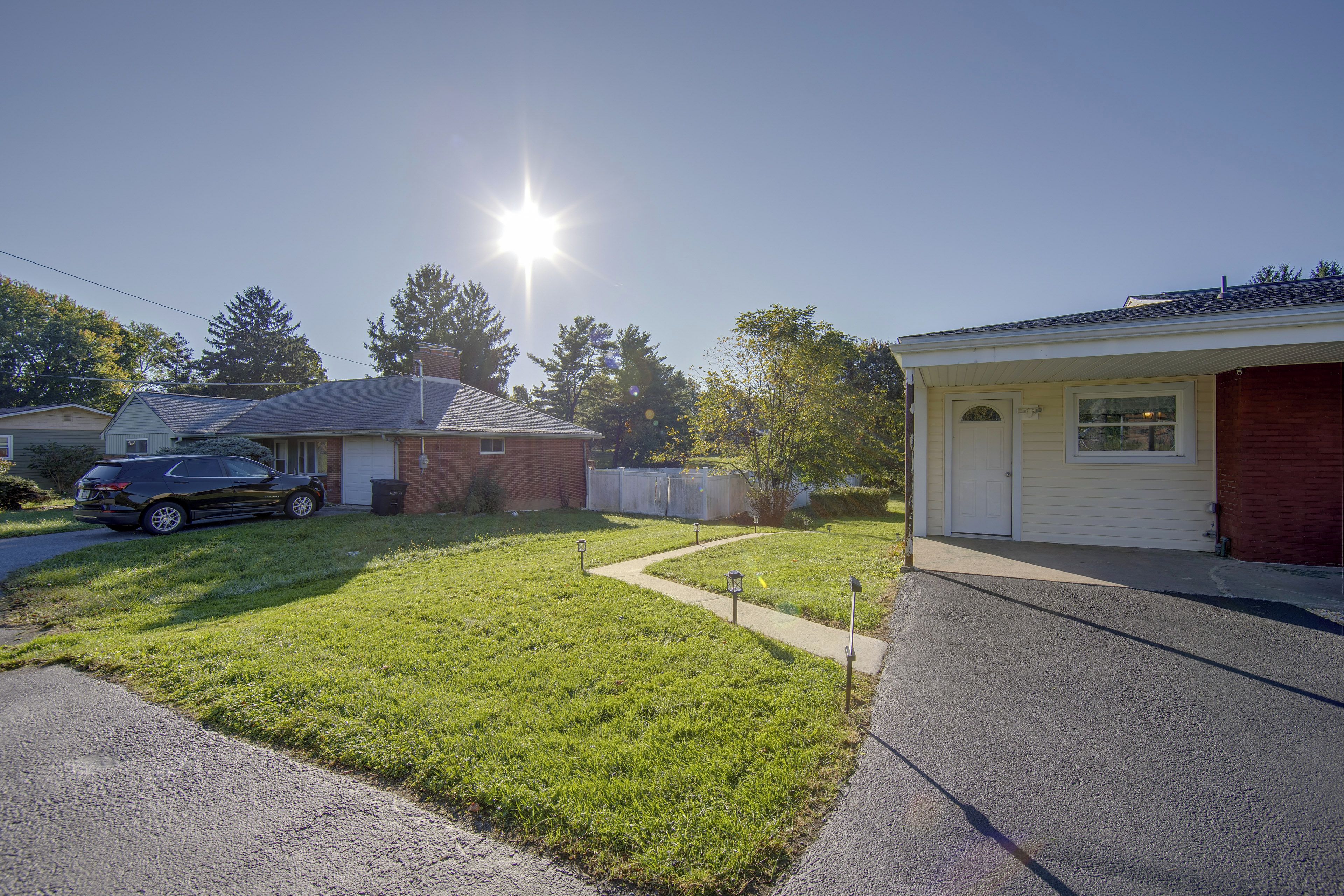 A residential area with houses, a driveway, and a parked car.
