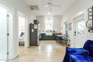 A modern kitchen with a dining area, wooden flooring, and a ceiling fan.