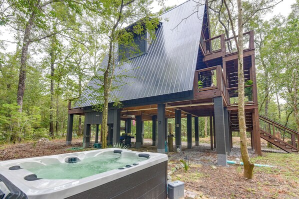 A wooden cabin with a hot tub in a forest setting.
