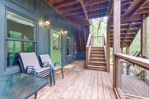 A wooden deck with outdoor seating and a staircase leading to a covered area.