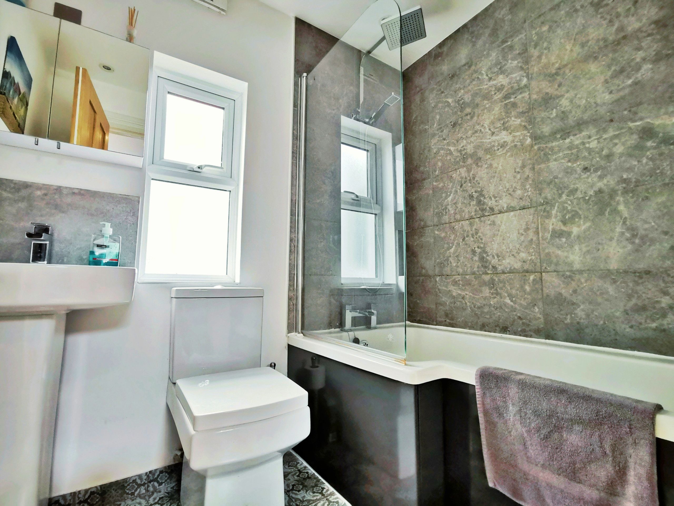 Ein Badezimmer mit Toilette, Waschbecken, Spiegel und Dusche.