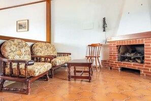 A living room with a fireplace, two armchairs, a small table, and a wooden floor. - Casa Yunger bright and spacious country villa, surrounded by greenery & garden. (Piazza)