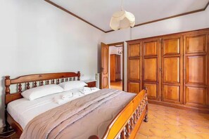 A bedroom with a wooden bed, a wardrobe, and a tiled floor. - Casa Yunger bright and spacious country villa, surrounded by greenery & garden. (Piazza)