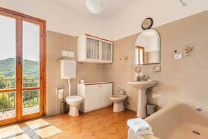 Casa de banho com sanita, bidé, lavatório e banheira.
