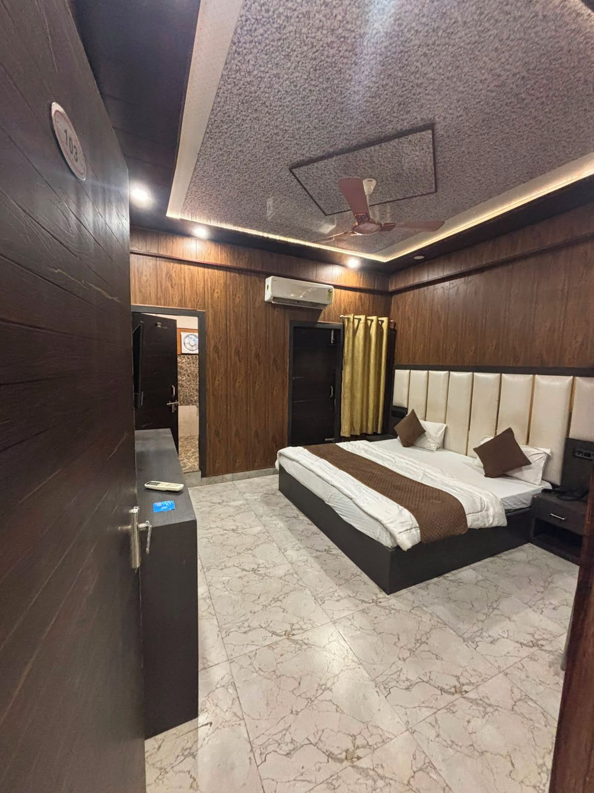A hotel room with a large bed, a wardrobe, an air conditioning unit, and a ceiling fan.