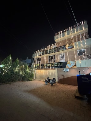 En bygning med flere etager, et skilt med 'AURIVIQUE Hotels and Banquets' og en parkeret motorcykel.