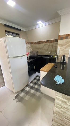 A kitchen with a refrigerator, stove, sink, and a wooden countertop.