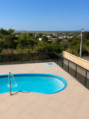 Una piscina amb vistes a una vila i a les colines al fons.