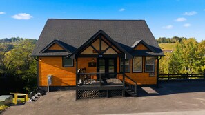 Een houten lodge met een veranda, een trap en uitzicht op het omliggende landschap.